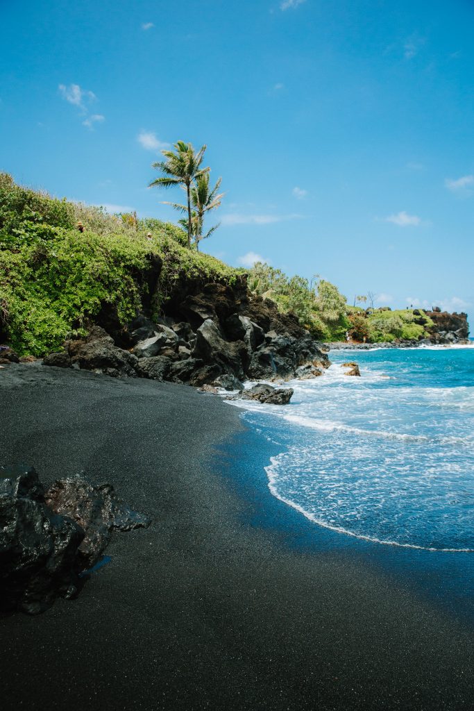 Black sand beach at Wai'anapanapa State Park surrounded by lava rocks, Hāna Maui