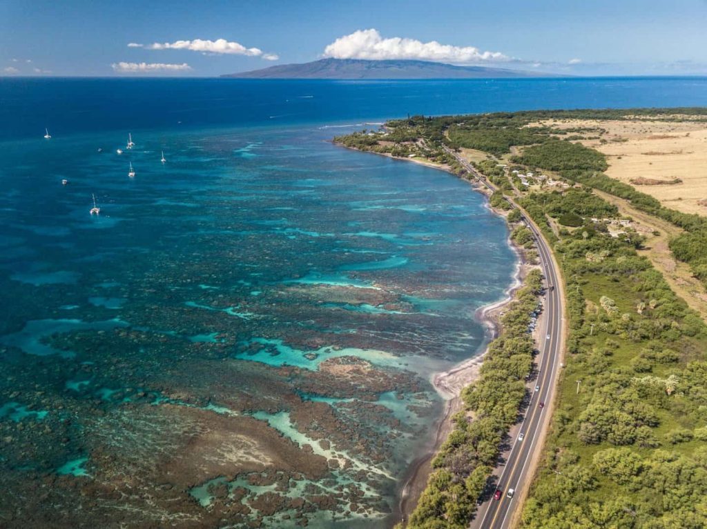 Aerial view of Olowalu Beach and reef near Mile Marker 14 on Honoapi'ilani Highway, West Maui, showing the narrow roadside beach and turquoise shallow water
